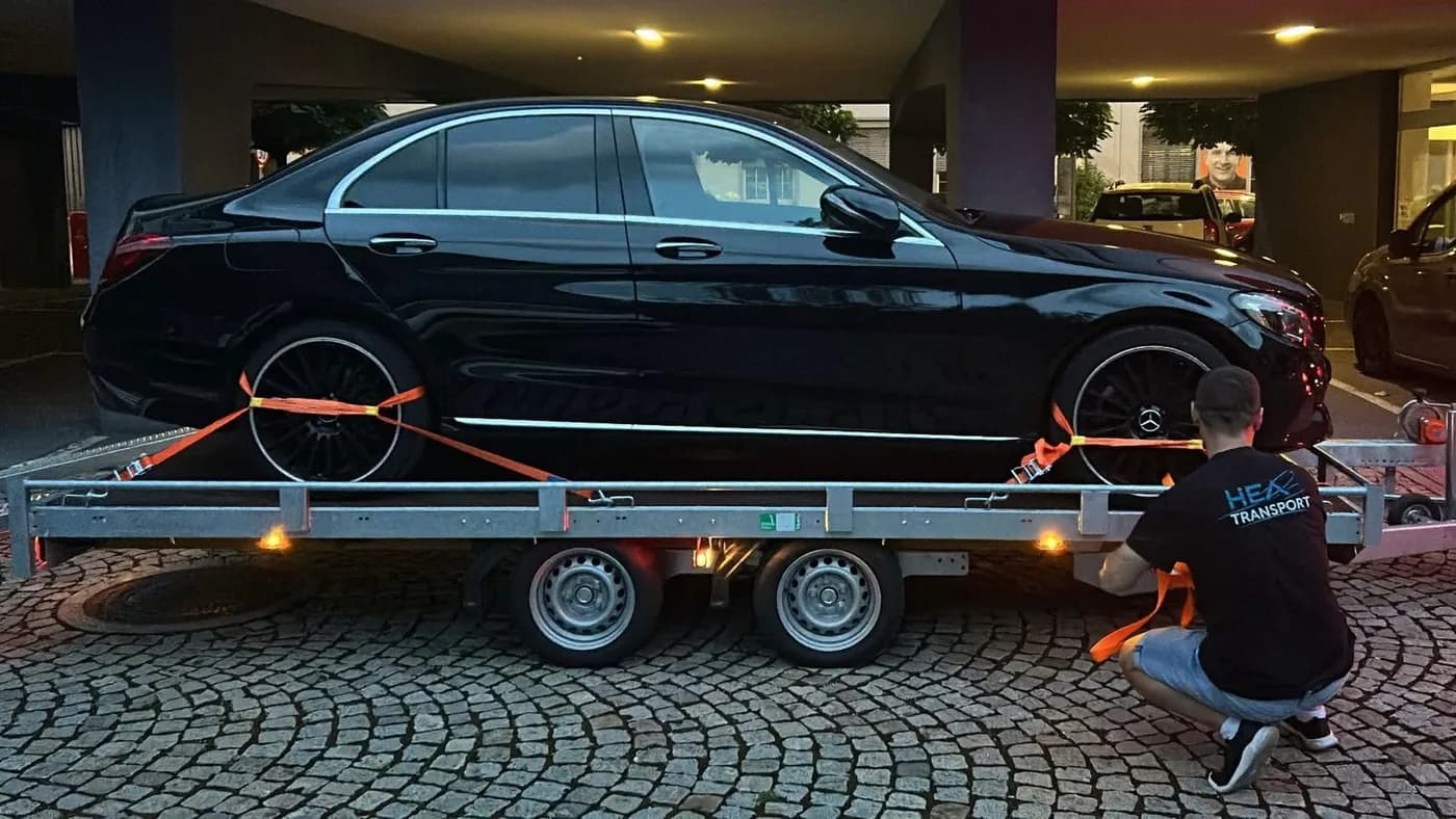 Schwarzer Mercedes sicher auf dem Anhänger von HEA Transporte verzurrt